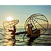 Myanmar travel attraction landmark - two traditional Burmese fishermen at Inle lake, Myanmar famous for their distinctive one legged rowing style on sunrise sunset