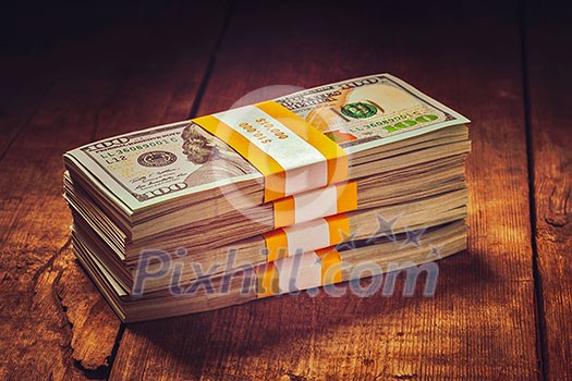 Creative business finance making money concept. Vintage retro effect filtered hipster style image of stacks of new 100 US dollars 2013 edition banknotes (bills) bundles isolated on wooden background