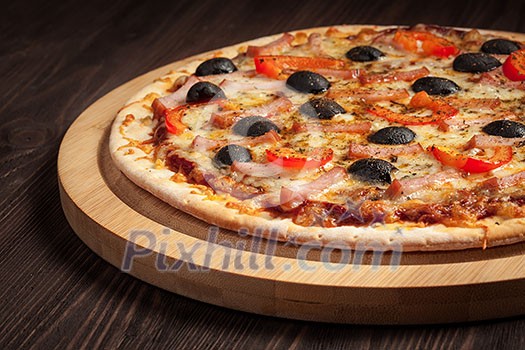 Ham pizza with capsicum and olives on wooden board on table close up Ham pizza with capsicum and olives on wooden board on table close up