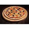 Ham pizza with capsicum and olives on wooden board on table