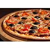 Ham pizza with capsicum and olives on wooden board on table close up