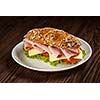 Ham sandwich with lettuce, cheese, tomato on plate on wooden table