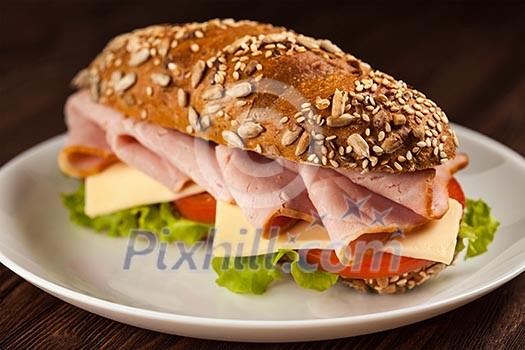 Ham sandwich with lettuce, cheese, tomato on plate on wooden table