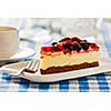 Dessert background - fruit cheese cake on plate with fork and coffee cup on blue checkered tablecloth