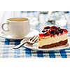 Dessert background - fruit cheese cake on plate with fork and coffee cup on blue checkered tablecloth