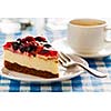 Dessert background - fruit cheese cake on plate with fork and coffee cup on blue checkered tablecloth