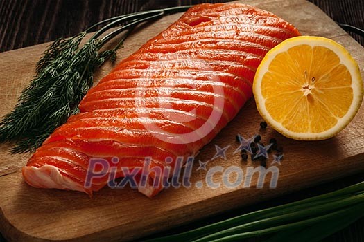 Fresh salmon piece on wooden cooking board with vegetables Fresh salmon piece on wooden cooking board with vegetables