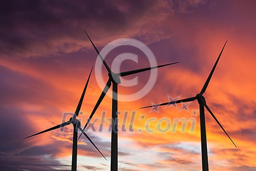 Green renewable energy concept - wind generator turbines in sky on sunset Green renewable energy concept - wind generator turbines in sky on sunset