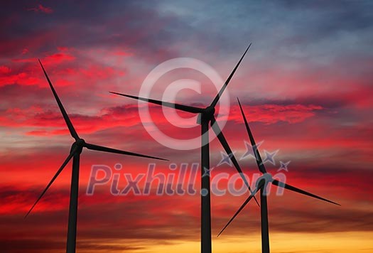 Green renewable energy concept - wind generator turbines in sky on sunset Green renewable energy concept - wind generator turbines in sky on sunset