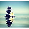 Vintage retro effect filtered hipster style Zen spa concept background - Zen massage stones with frangipani plumeria flower in water reflection