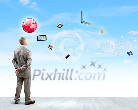 Back view of confident businessman looking at items flying in air Back view of confident businessman looking at items flying in air