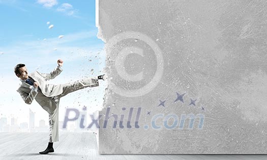 Businessman breaking stone wall with karate kick Businessman breaking stone wall with karate kick