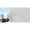 Businessman breaking stone wall with karate punch