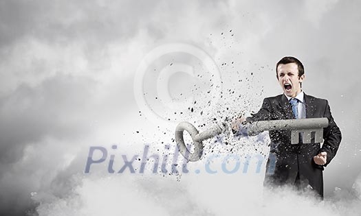 Angry businessman crashing stone key with punch Angry businessman crashing stone key with punch