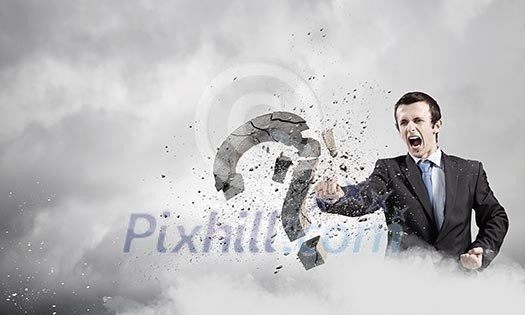 Businessman breaking stone question mark with karate kick
