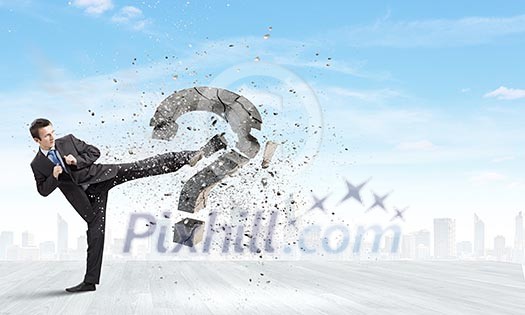 Businessman breaking stone question mark with karate kick Businessman breaking stone question mark with karate kick