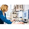 Pretty, female researcher using a microscope in a lab, doing research (color toned image)