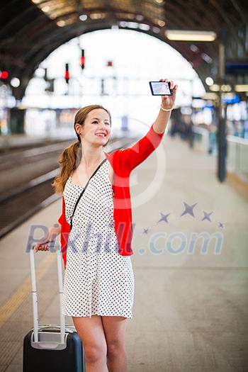 Pretty young woman at a train station - taking a selfie with her smart phone