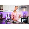 Pretty, young woman posing in her modern kitchen, holding a wooden spoon, ready to cook something delicious (shallow DOF; color toned image)