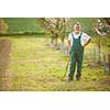 Portrait of a handsome senior man gardening in his garden, on a lovely spring day (color toned image)