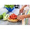 Young woman cutting vegetables in her modern kitchen - fixing a salad