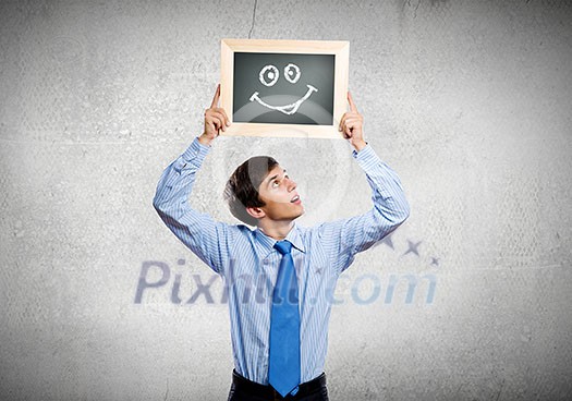 Young happy businessman holding frame with drawn smile