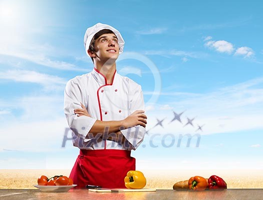 Young cheerful cook and ingredients flying in air Young cheerful cook and ingredients flying in air