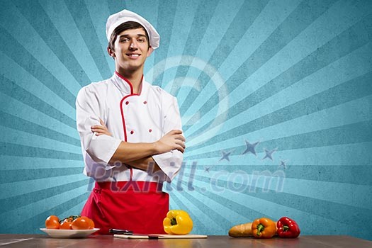 Young cheerful cook and ingredients flying in air Young cheerful cook and ingredients flying in air