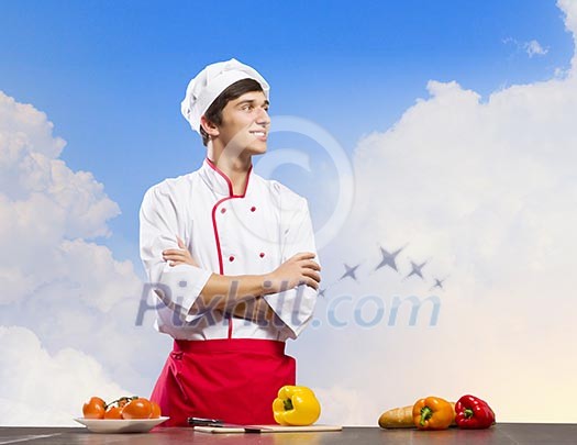 Young cheerful cook and ingredients flying in air