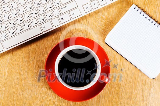 Cup of coffee notepad and keyboard on wooden table