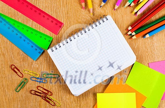 Colored pencils and notepad on wooden table