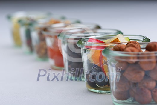 nuts and dry fruits mix healthy organic food mix in glass bowls isolated on white background