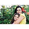 beautiful mom and daughter outdoor in garden  together with flower have fun and hug 