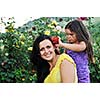 beautiful mom and daughter outdoor in garden  together with flower have fun and hug 