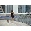 beautiful happy young  woman in black dress with cute small dog puppy have fun on street