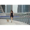 beautiful happy young  woman in black dress with cute small dog puppy have fun on street