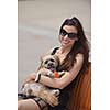 beautiful happy young  woman in black dress with cute small dog puppy have fun on street