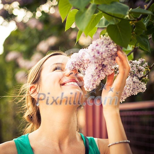 Beautiful young woman smelling white jasmin flowers