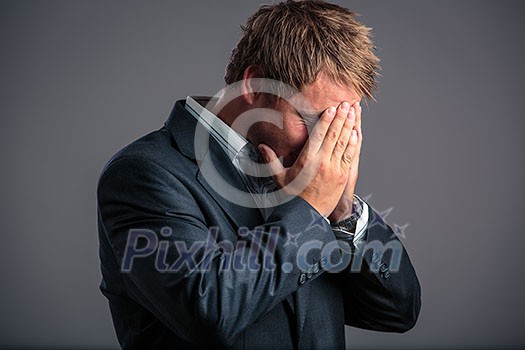 Businessman in depression with hands on forehead, hoping for better days to come as he has just hit the bottom