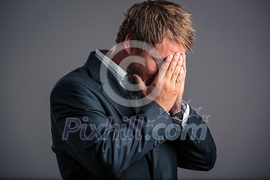 Businessman in depression with hands on forehead, hoping for better days to come as he has just hit the bottom Businessman in depression with hands on forehead, hoping for better days to come as he has just hit the bottom