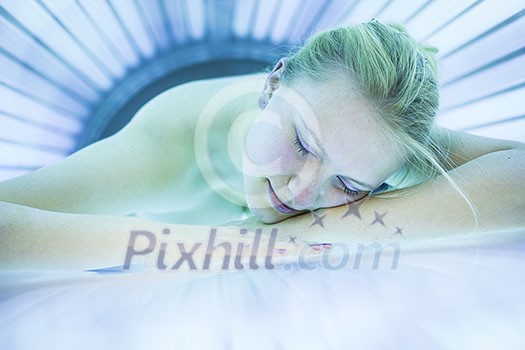 Pretty young woman tanning her skin in a modern solarium Pretty young woman tanning her skin in a modern solarium