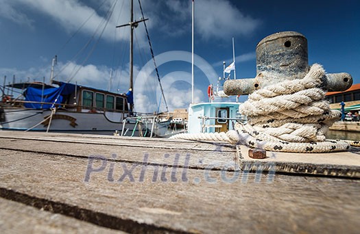 Boat docking point at a marina - rope fixed around a belay in a small harbor Boat docking point at a marina - rope fixed around a belay in a small harbor
