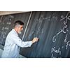 Senior chemistry professor writing on the board while having a chalk and blackboard lecture (shallow DOF; color toned image)