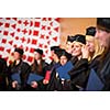 Pretty female college graduate at graduation with classmates, holding their degres. looking happy about their accomplishment