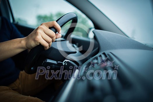 Male driver's hands driving a car on a highway (color toned image; shallow DOF)