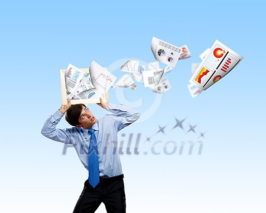 Young businessman holding frame above head with papers flying out