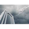 Bottom image of skyscraper with thunder lightning in sky