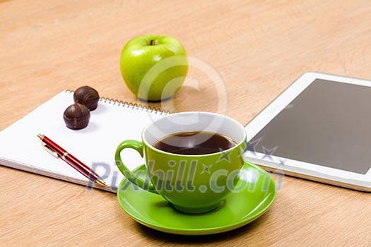 Tablet pc cup of coffee and notepad at table