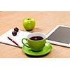 Tablet pc cup of coffee and notepad at table