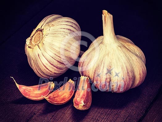 Vintage retro effect filtered hipster style image of garlic and cloves on old wooden background Vintage retro effect filtered hipster style image of garlic and cloves on old wooden background
